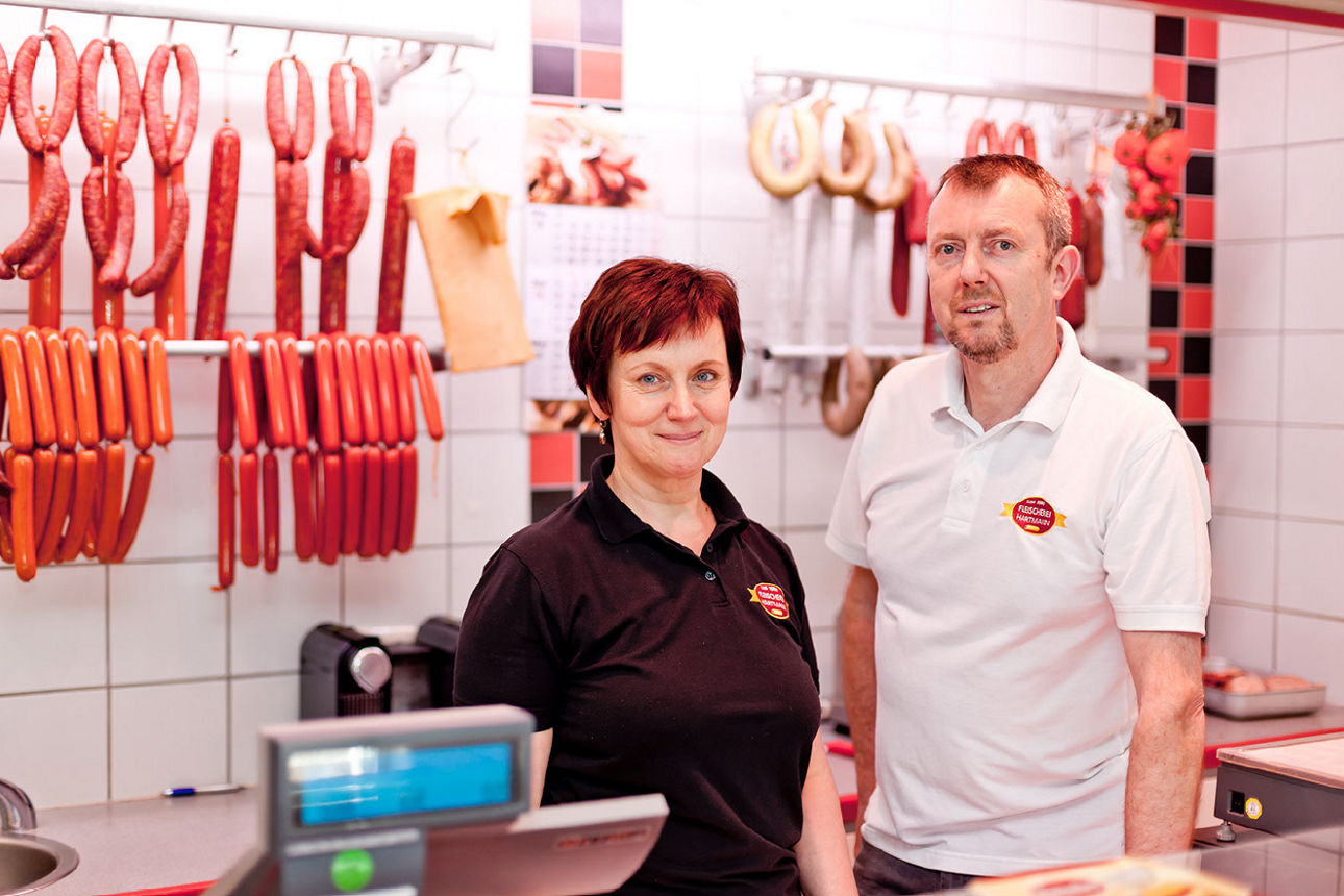 Herr und Frau Hartmann hinter dem Verkaufstresen in der Fleischerei