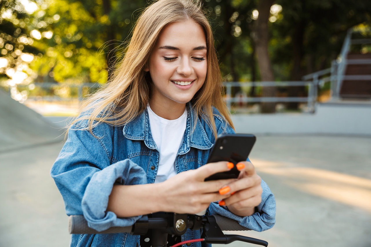 Ein lächelndes Mädchen schaut auf ihr Handy