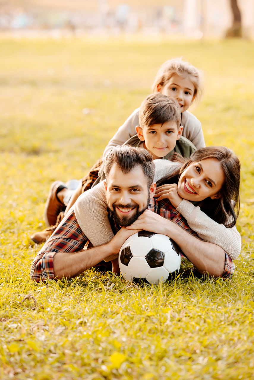 Familie liegt mit einem Fußball im Gras