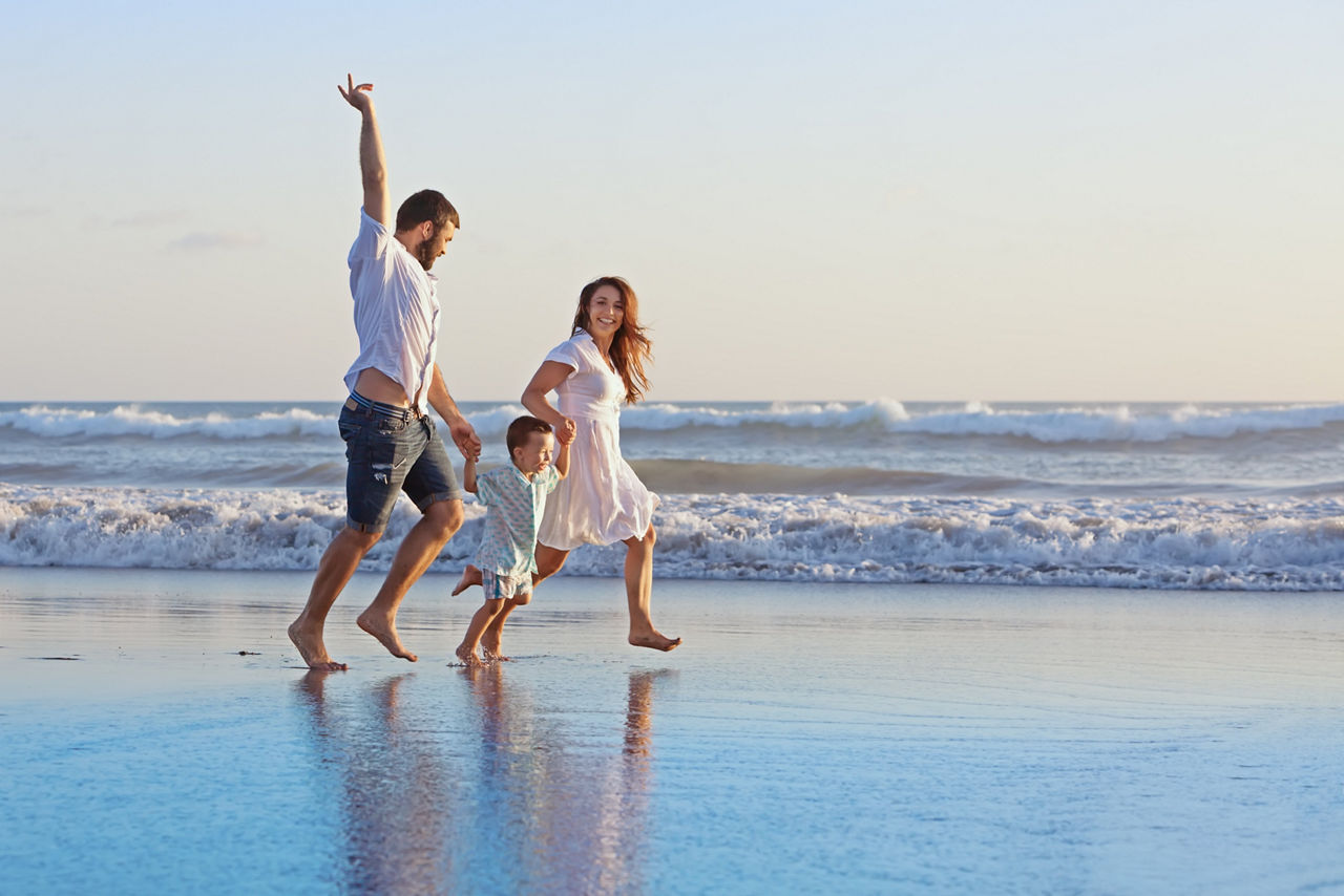 Eine Familie rennt glücklich am Strand entlang