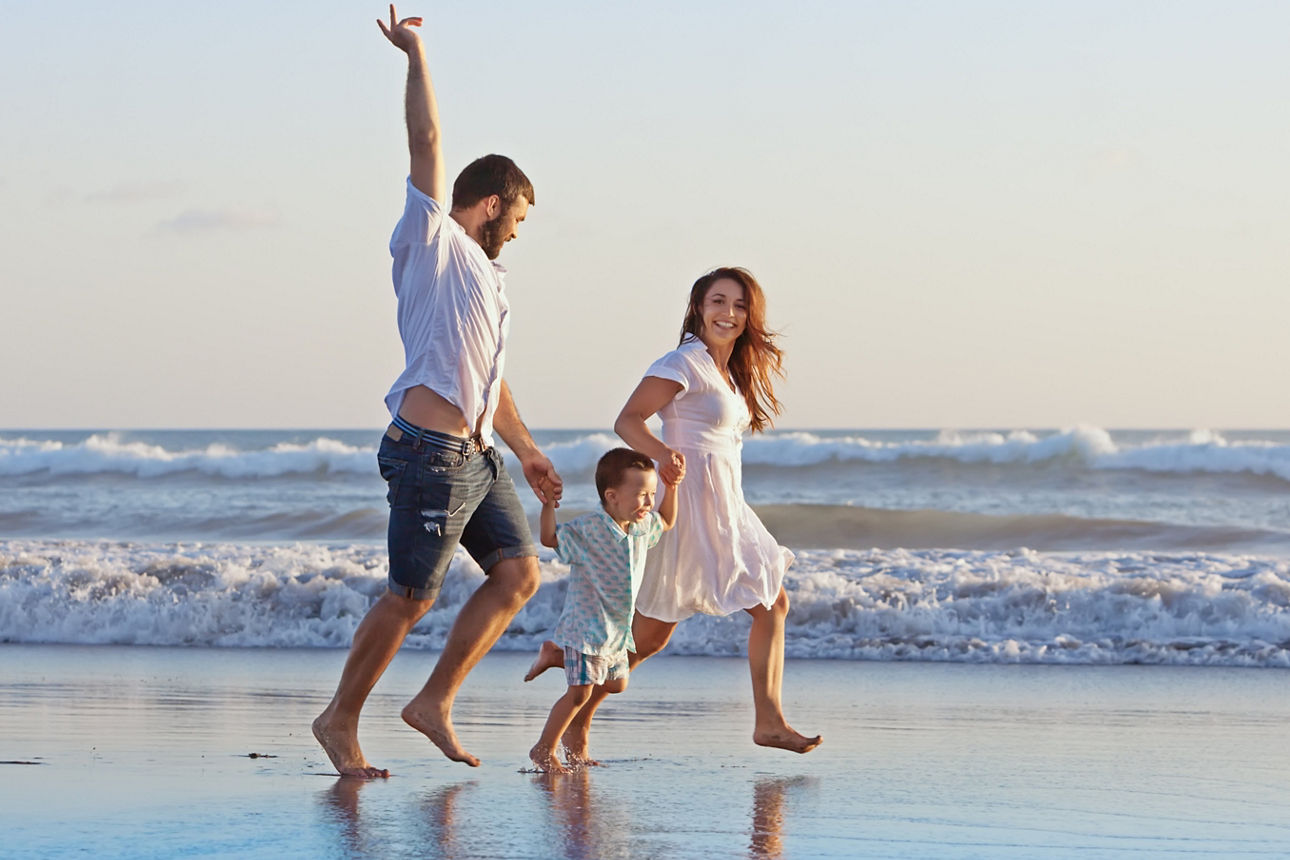 Eine Familie rennt glücklich am Strand entlang