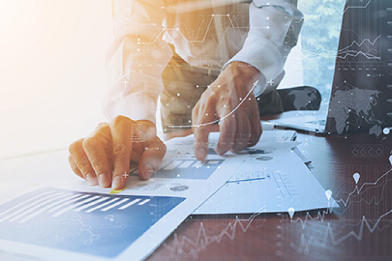 Mann zeigt auf Diagramme, die vor ihm liegen