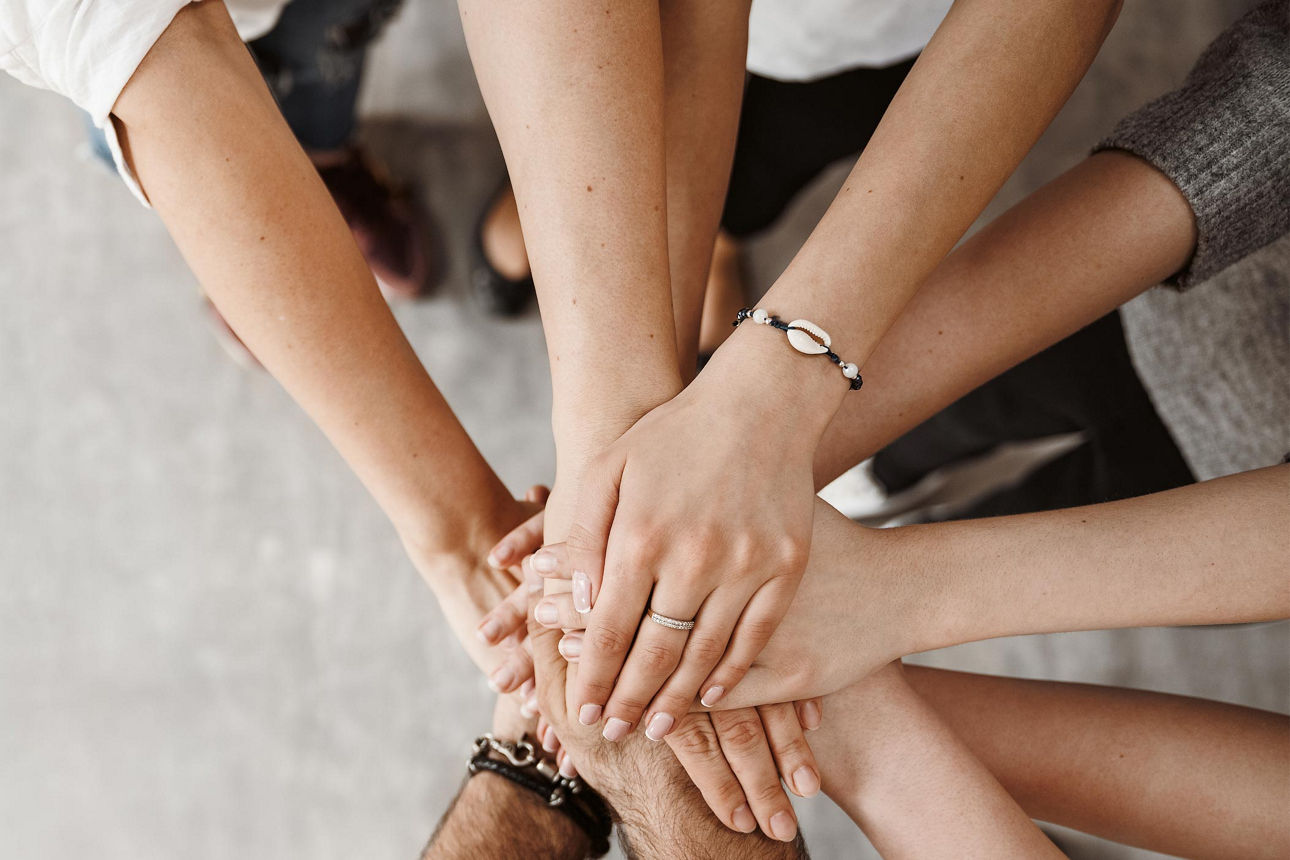 Auf dem Bild sind mehrere Hände zu sehen, die aufeinandergelegt sind.