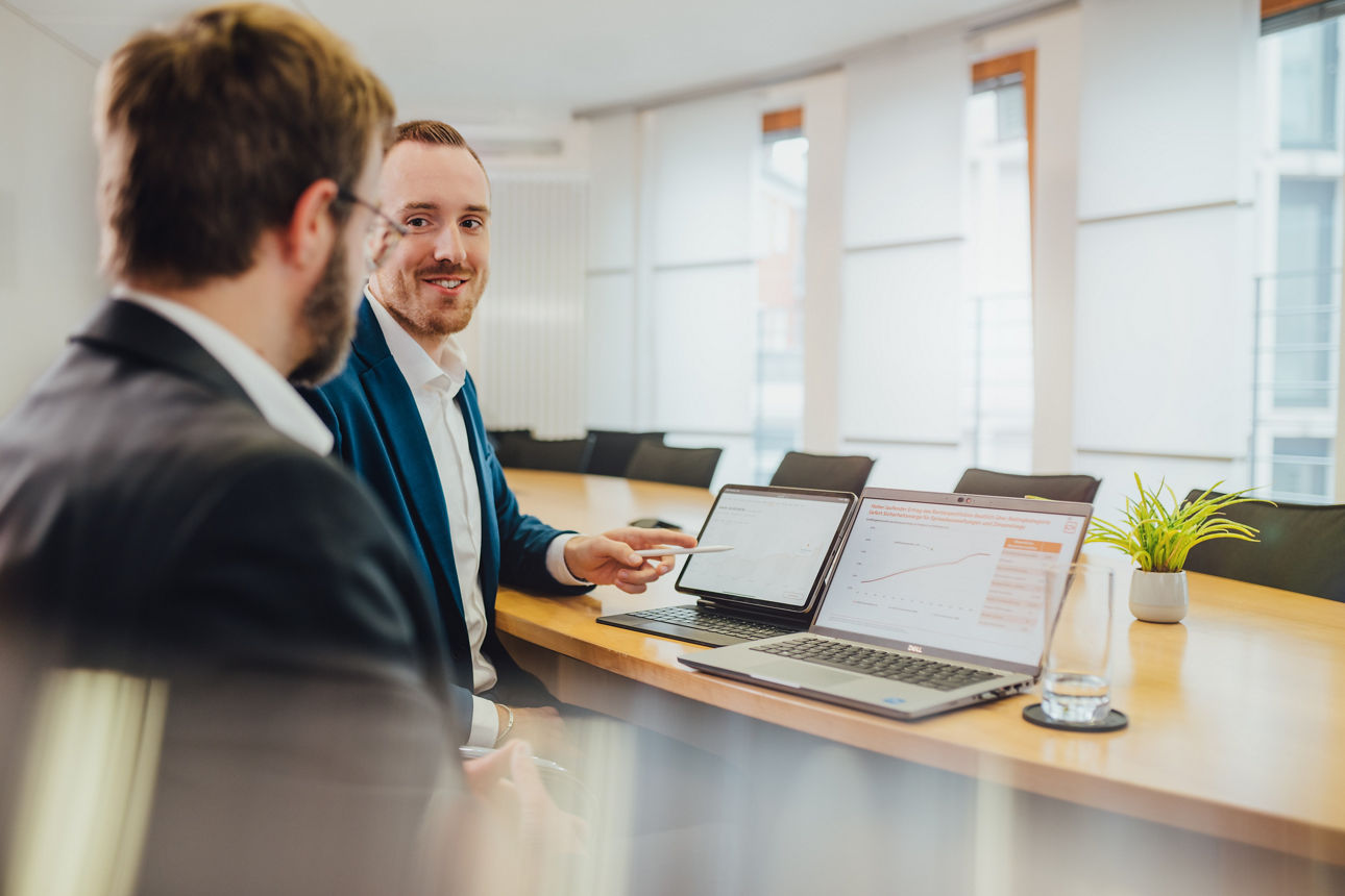 Gespräch zwischen zwei Mitarbeitenden, die auf einen Laptop schauen
