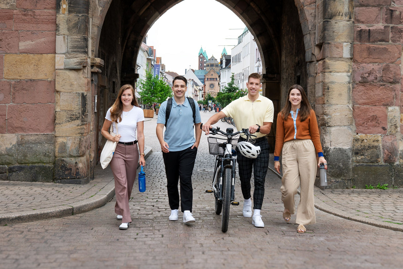 Vier Jugendliche laufen gut gelaunt durch ein historisches Stadttor