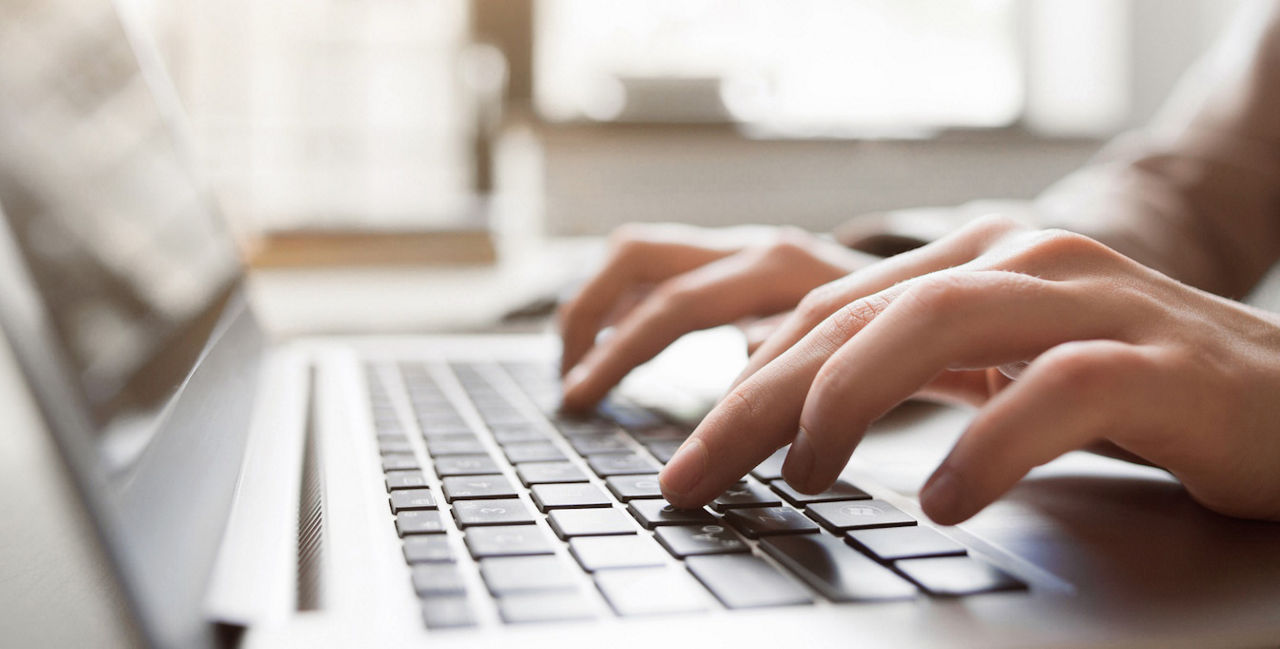 Hände tippen auf einer Laptop-Tastatur