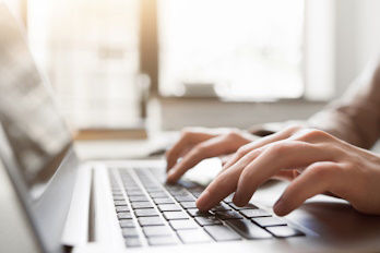 Hände tippen auf einer Laptop-Tastatur