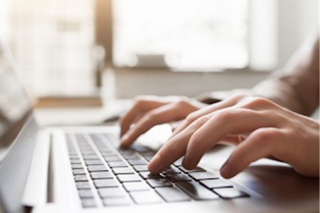Hände tippen auf einer Laptop-Tastatur