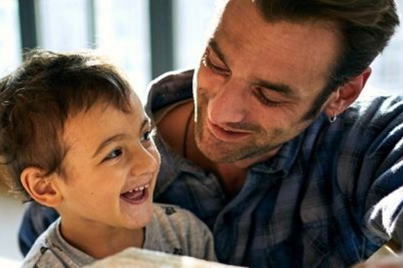 Ein Vater steht neben seinen zwei lachenden Kindern