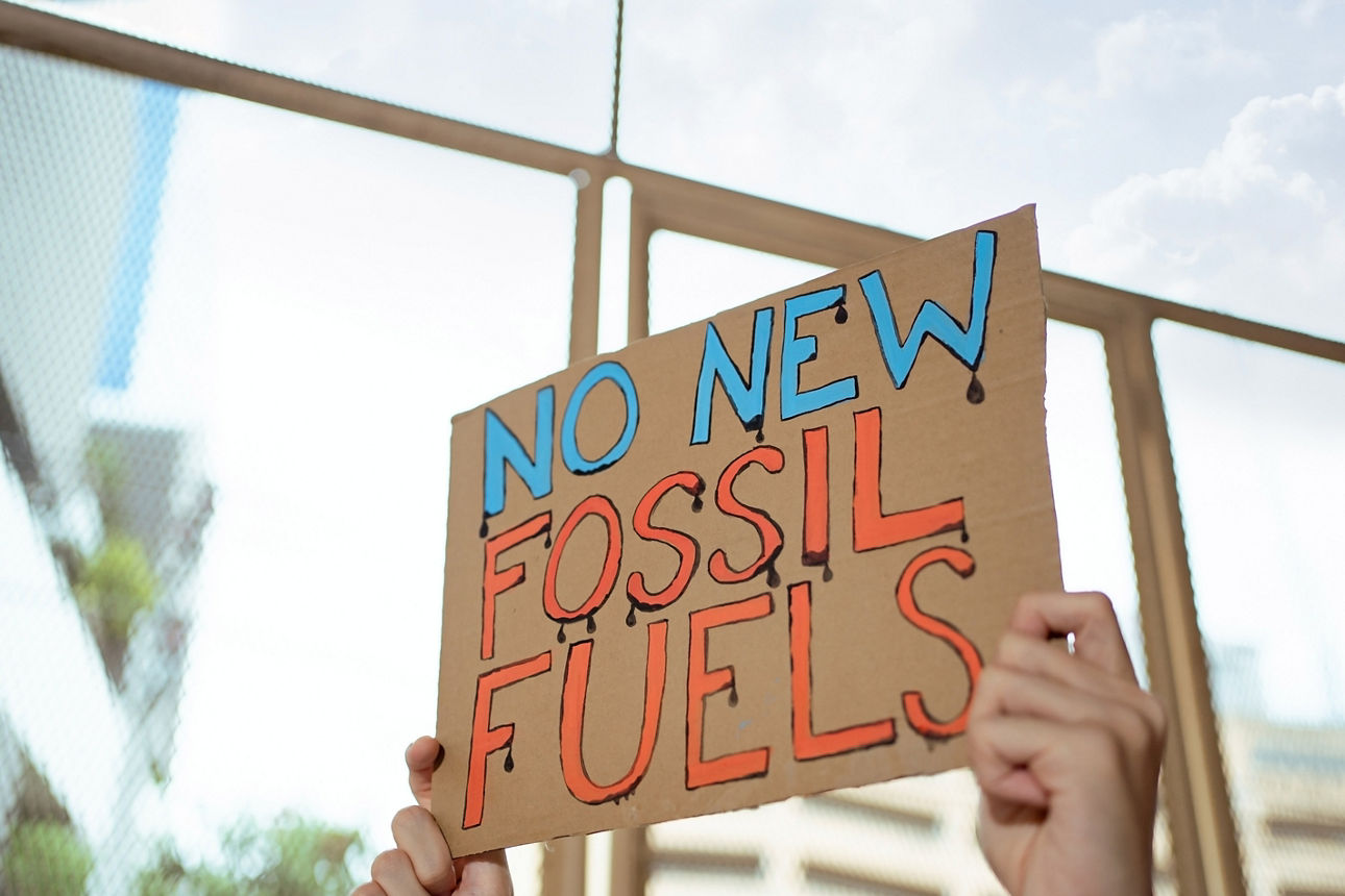 Eine Person hält ein Schild hoch mit den Worten "No New Fossil Fuels"