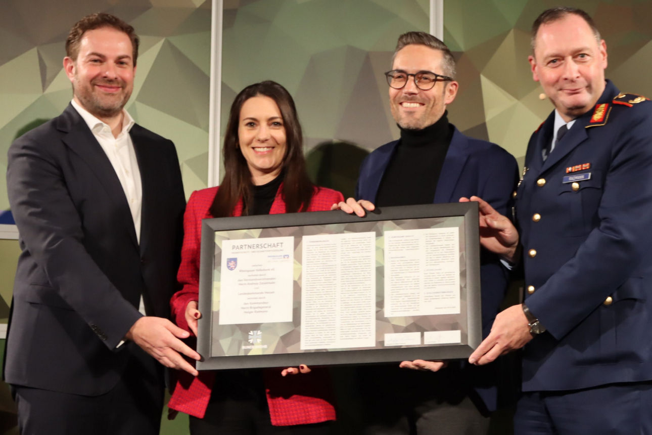 Vier Personen stehen nebeneinander und halten gemeinsam einen gerahmten Text mit Auszeichnung