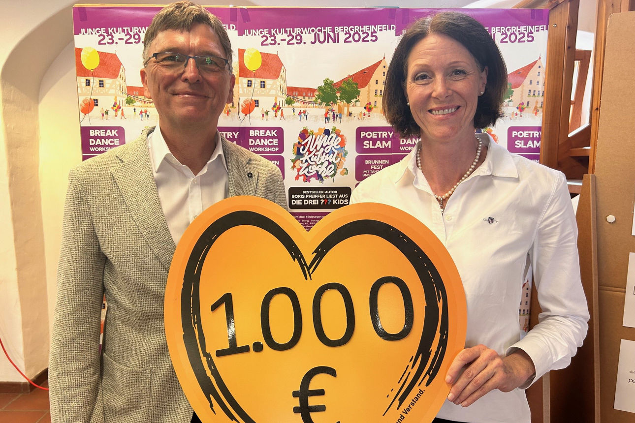 Frau und Mann halten lächelnd ein Herz mit Spendensumme 1.000 Euro