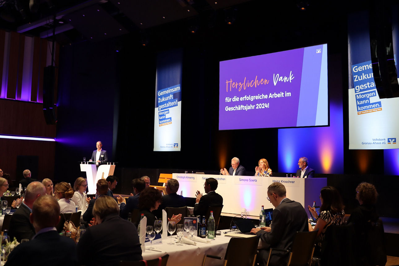 Eine Bühne mit Personen drauf und Zuschauern. 