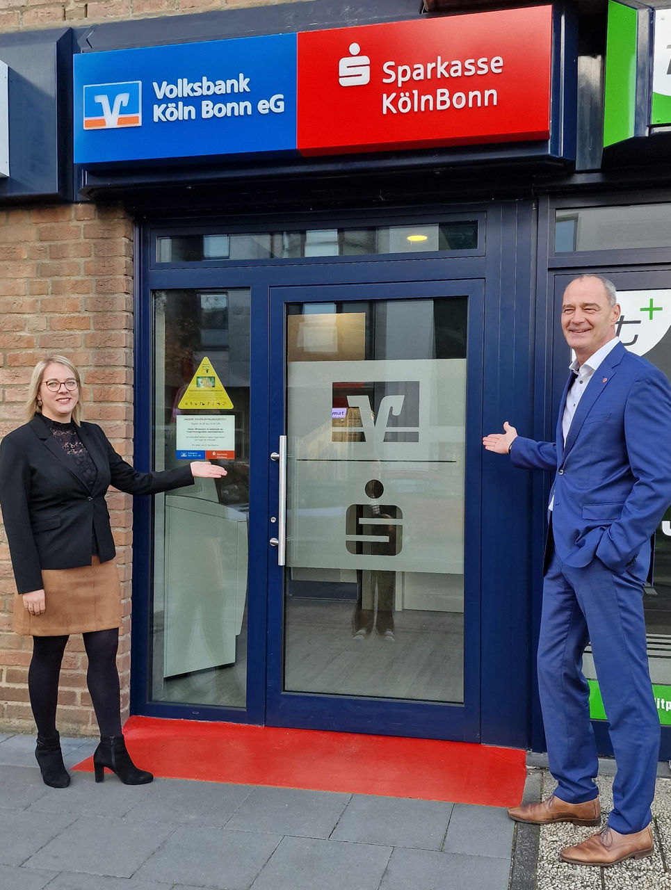 Bitte treten Sie ein! - Volksbank-Bereichsdirektor Stefan Dohmen und Sparkassen-Bereichsleiterin Martina Westebbe eröffnen ihrer Kundschaft neue Möglichkeiten - hier am Standort Widdersdorf / Fotograf: Jörg Wehner / Bildrechte: Sparkasse KölnBonn