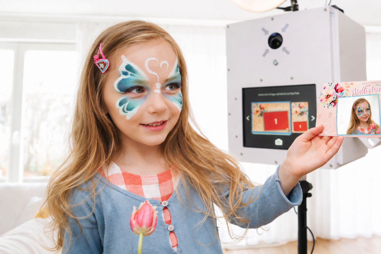 Kind mit Kinderschminke vor einer Fotobox