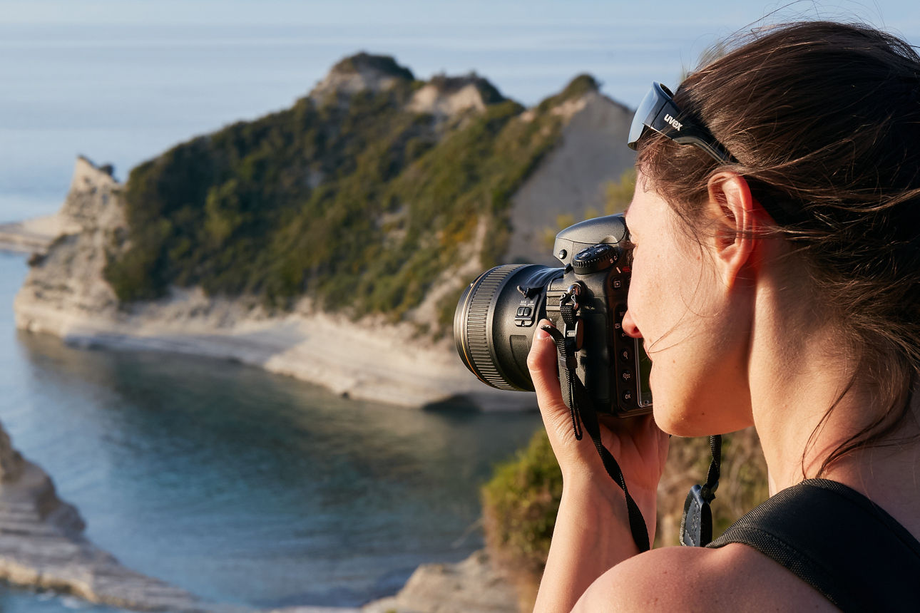 Junge Frau fotografiert die felsige Küste von Korfu, Griechenland