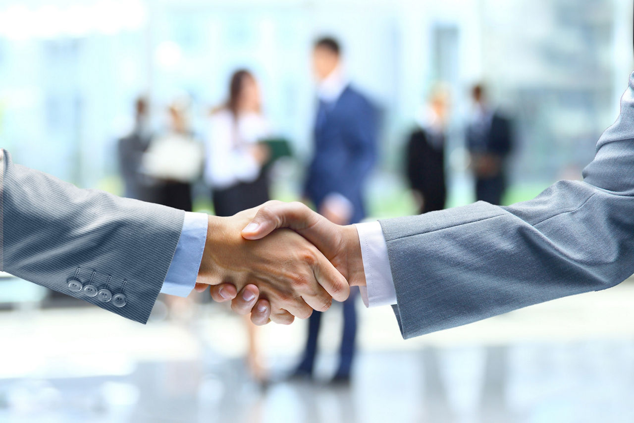 Zwei Männer im Anzug begrüßen sich per Handshake