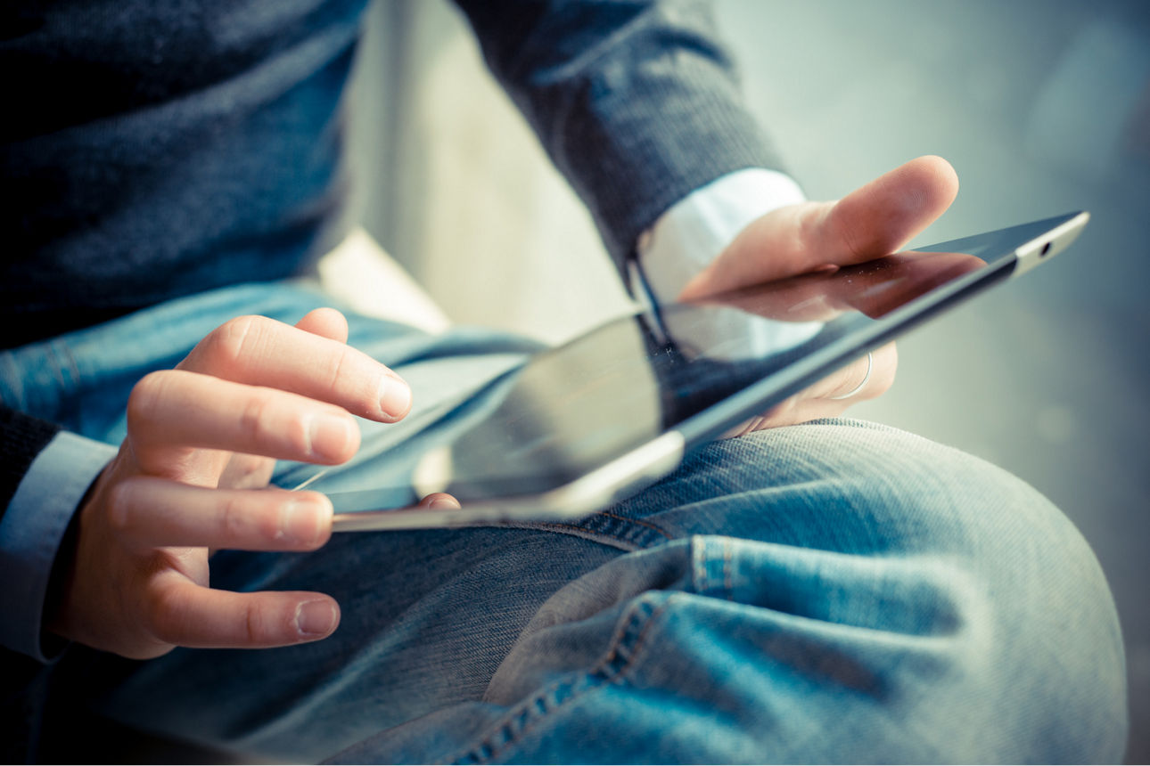 Mann sitzend mit einem Tablet in der Hand