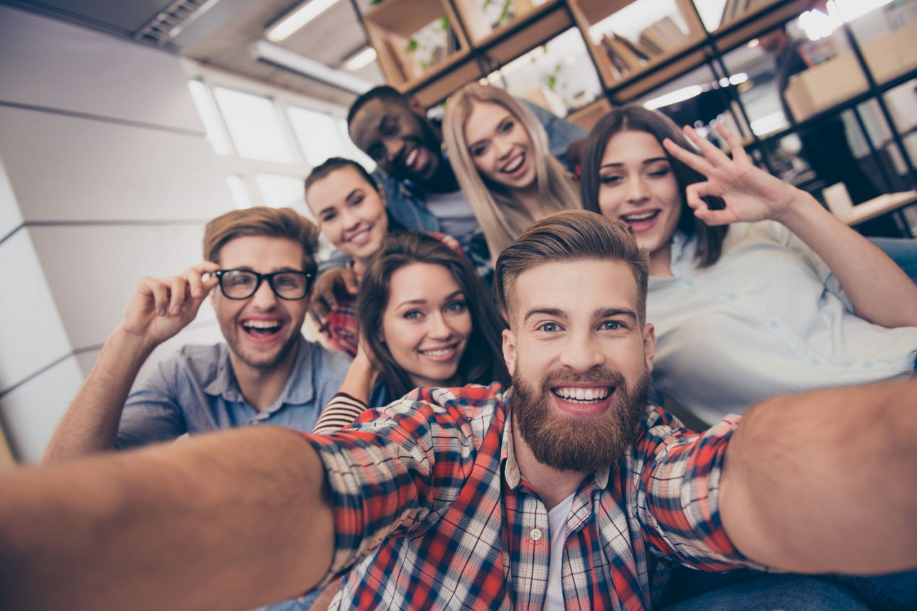 Eine Gruppe von jungen Menschen lacht in der Kamera und macht ein Selfie