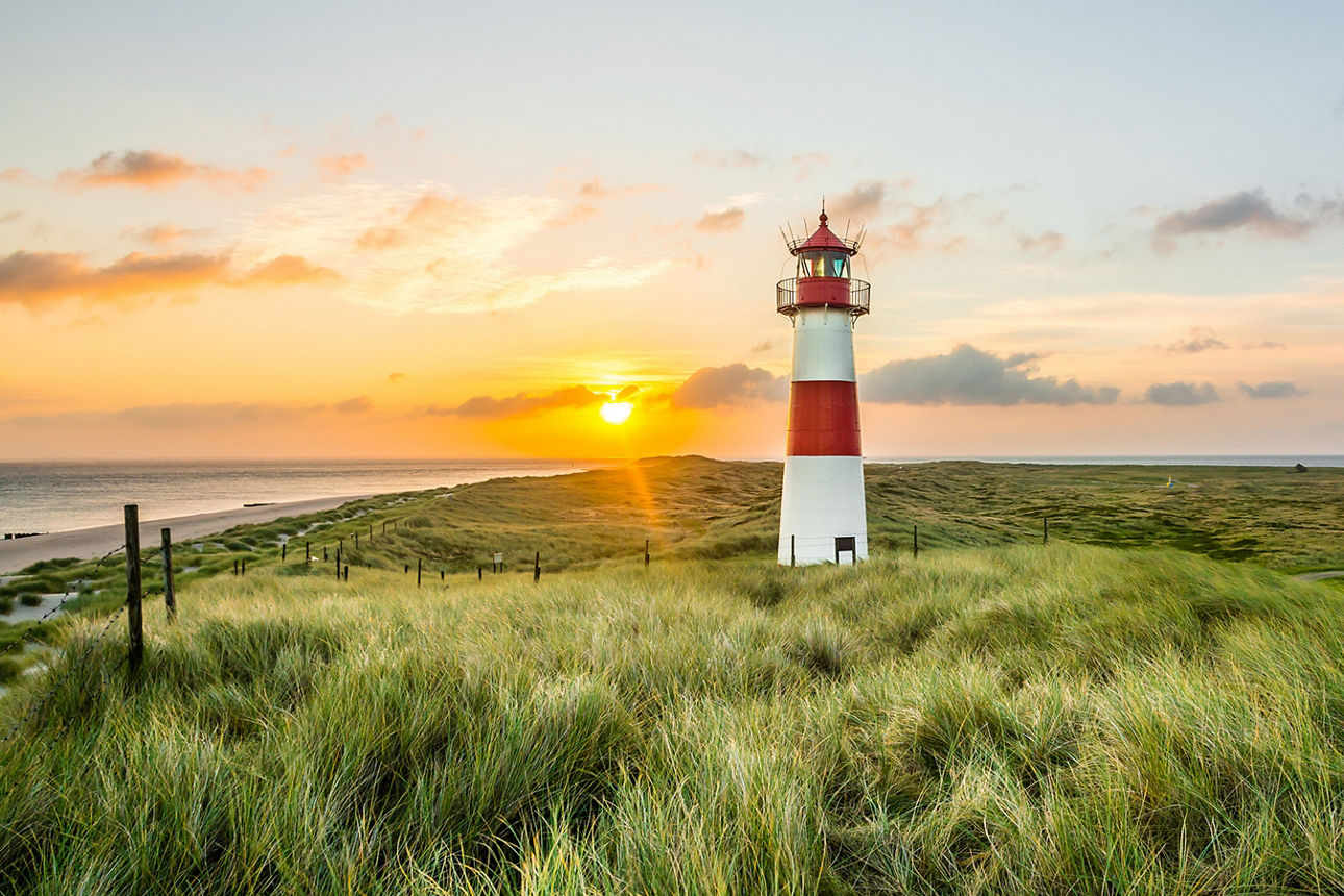 Leuchttrum am Strand bei untergehender Sonne