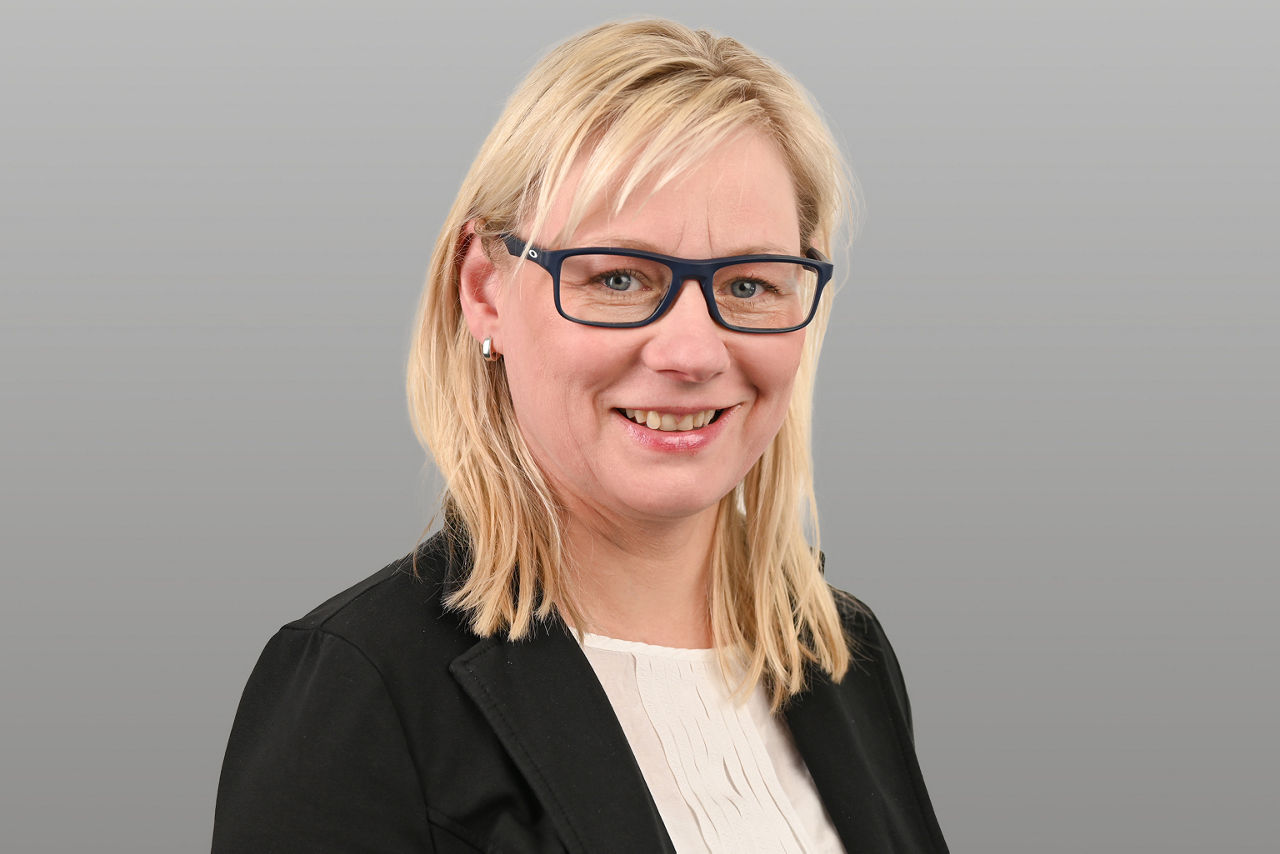Privatkundenberaterin Ulrike Frölich vor grauen Hintergrund
