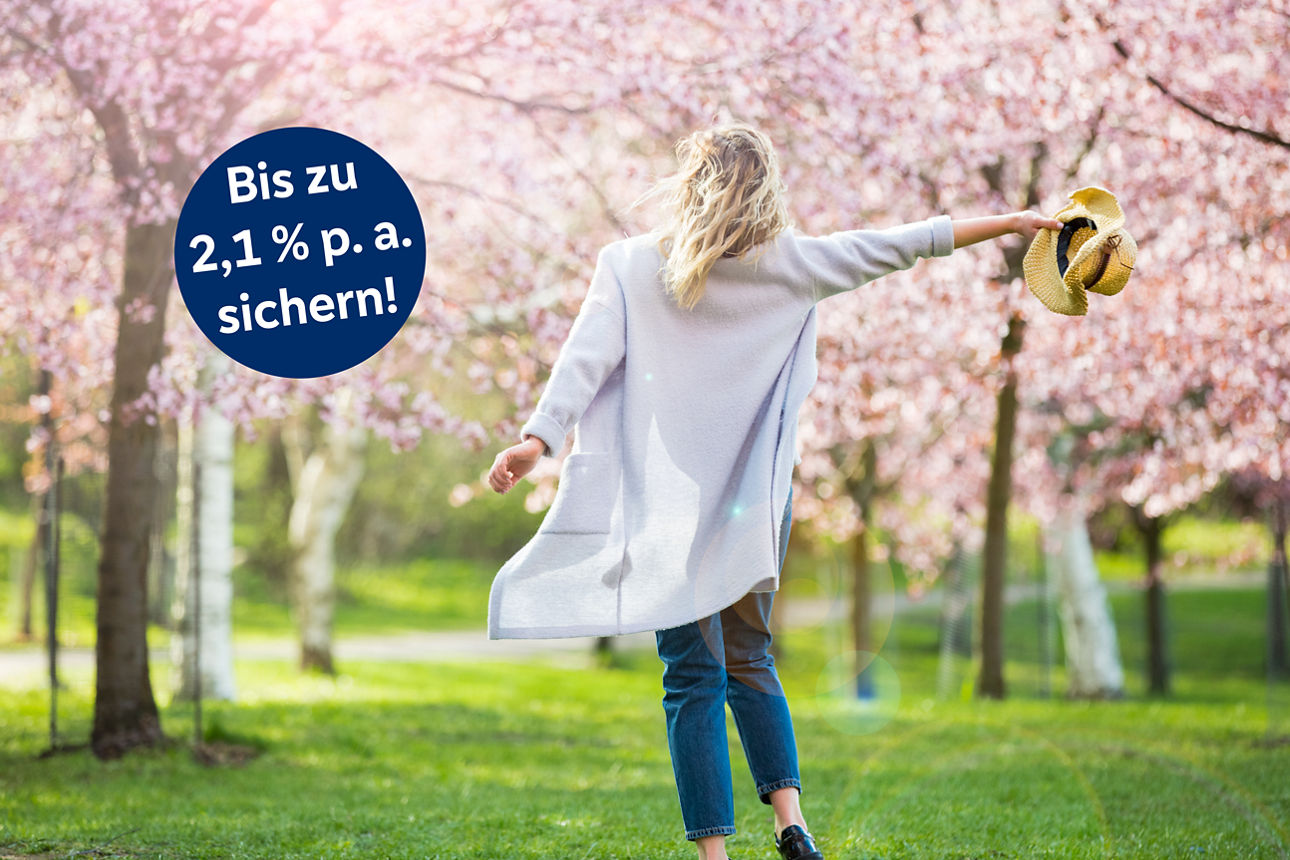 Frau freut sich über Frühling und Bäume mit Kirschblüte