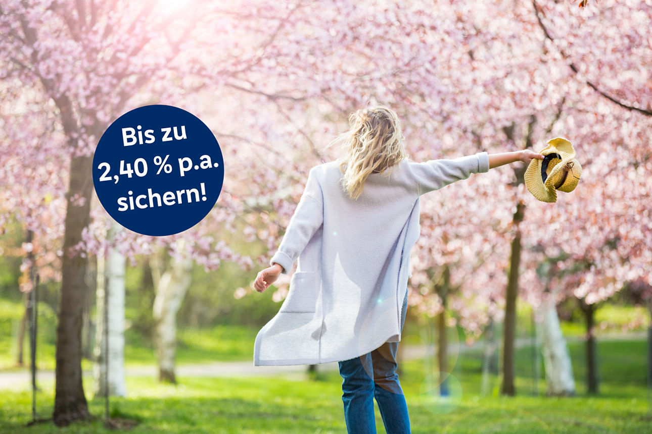 Frau mit Hut in der Hand vor blühenden Kirschbäumen