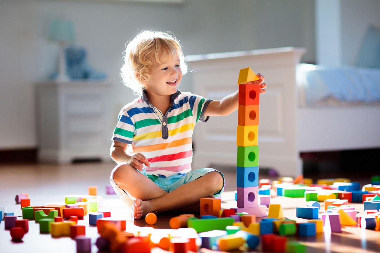 Ein kleiner Junge sitzt in seinem Zimmerund spielt mit Bauklötzen