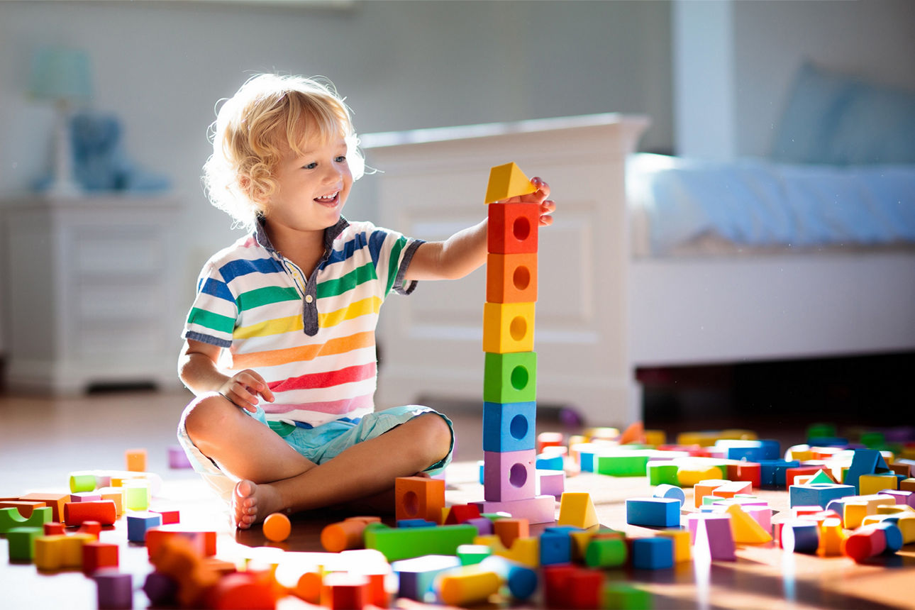 Ein kleiner Junge sitzt in seinem Zimmerund spielt mit Bauklötzen