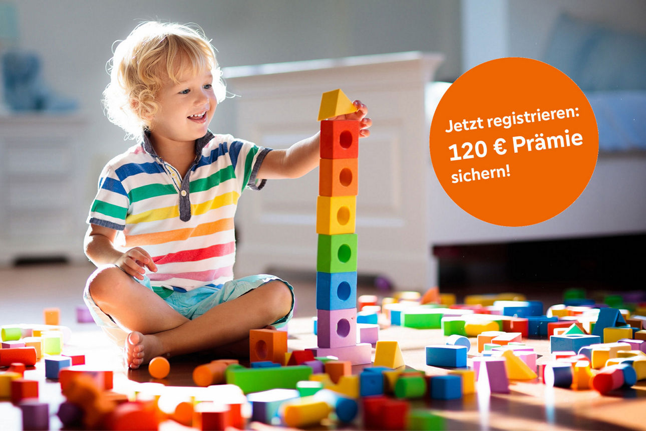 Kind sitzt in seinem Zimmer auf dem Boden und spielt mit Bauklötzen