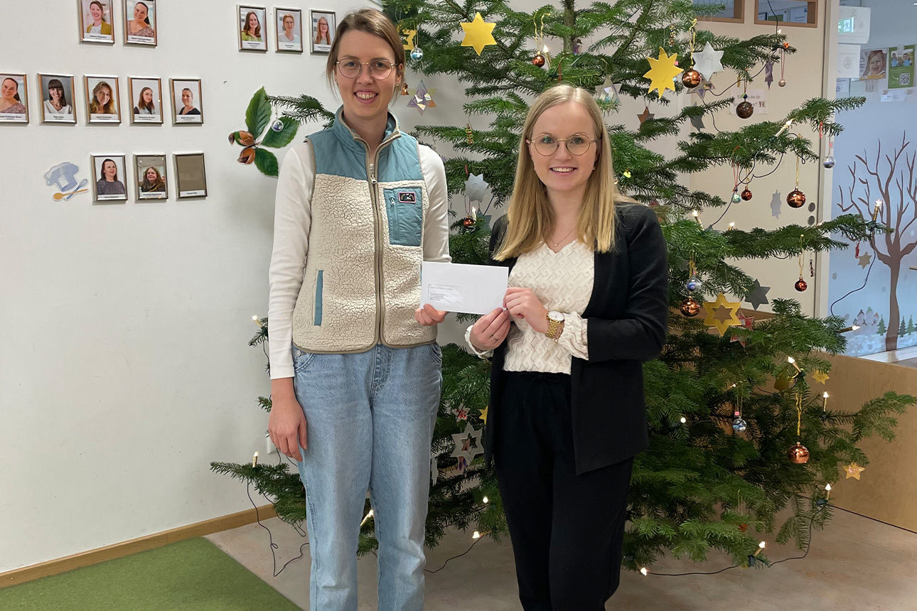 Zwei junge Frauen lachen in die Kamera. Sie halten einen Briefumschlag in der Hand.