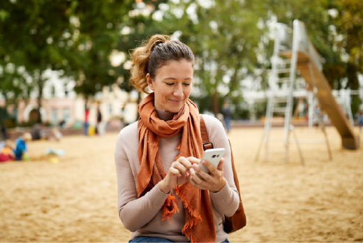 Frau im Park, die auf ihr Smartphone schaut