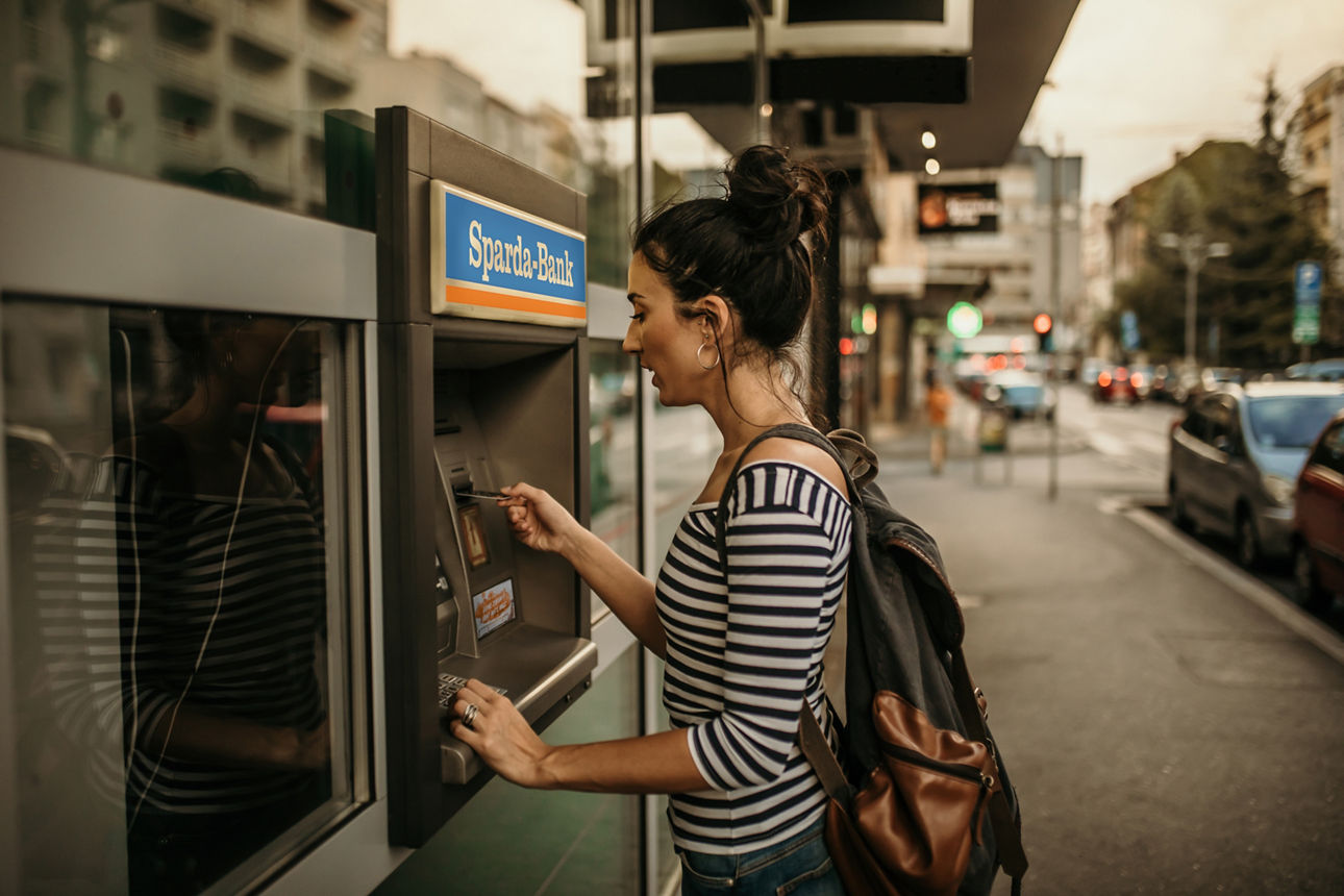 Junge Frau hebt Geld an einem Geldausgabeautomaten ab