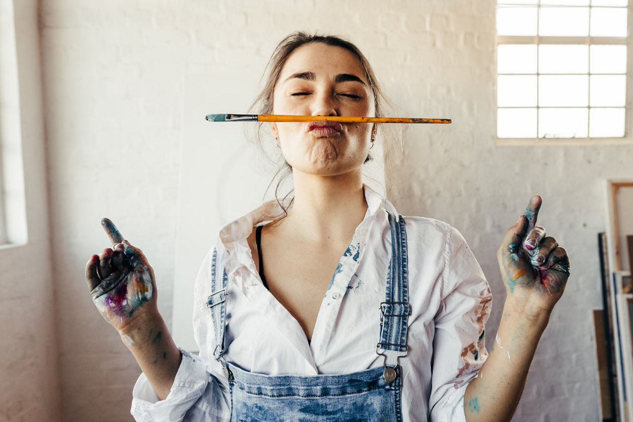 Frau mit Pinsel und farbigen Händen in einem Atelier