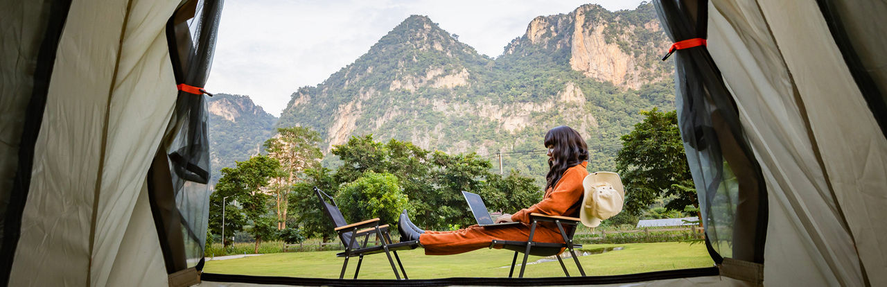 Frau mit Laptop vor einem Zelt