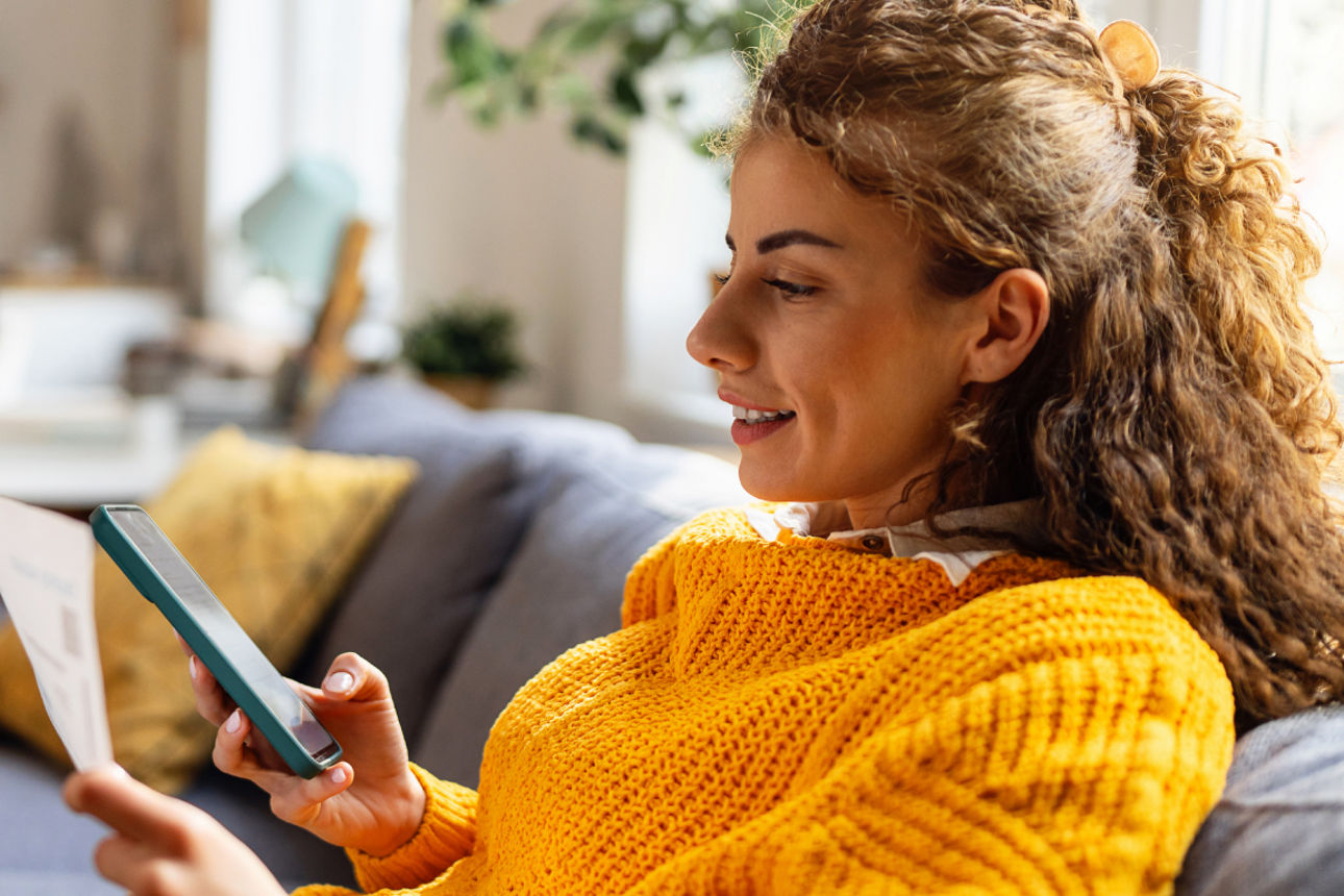 Frau mit Smartphone sitzt auf Sofa