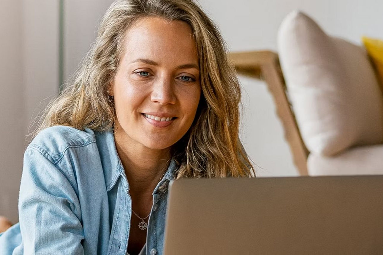 Eine Frau liegt im Wohnzimmer vor dem Notebook