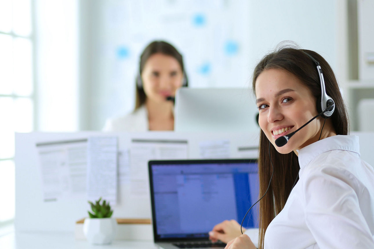 Frau mit Headset lächelt freundlich den Betrachter an