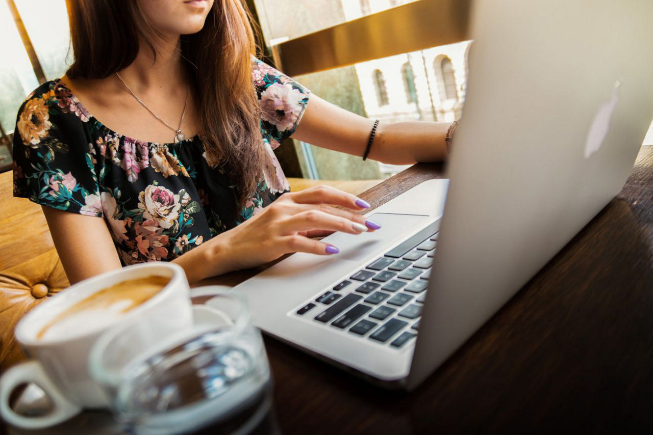Frau am PC mit Tasse und Glas