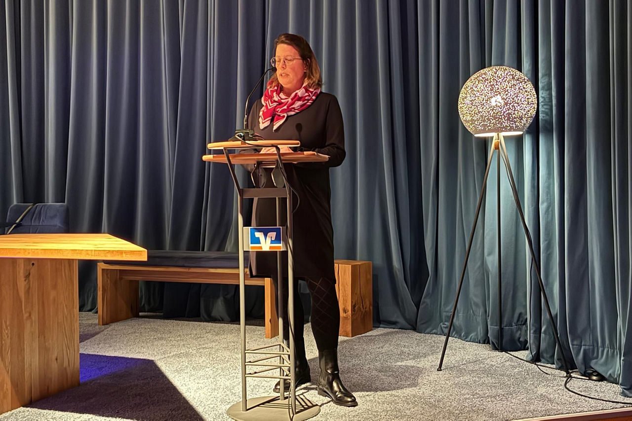 Nicole Dembowski steht in einem schwarzen Kleid an einem Rednerpult auf der kleinen Bühne der Reformierten Kirche in Schermbeck.