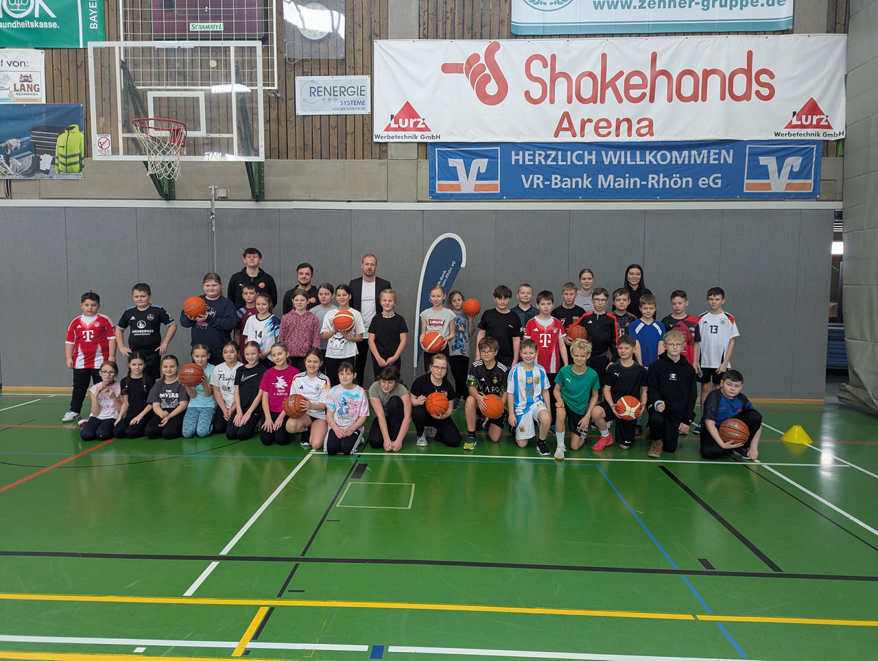 Zu sehen ist das das Jugendtrainerteam des Freak City Bamberg e.V. mit Schülerinnen und Schülern der fünften Jahrgangsstufe des Gymnasiums Bad Königshofen. Das Foto wurde in einer Turnhalle gemacht.