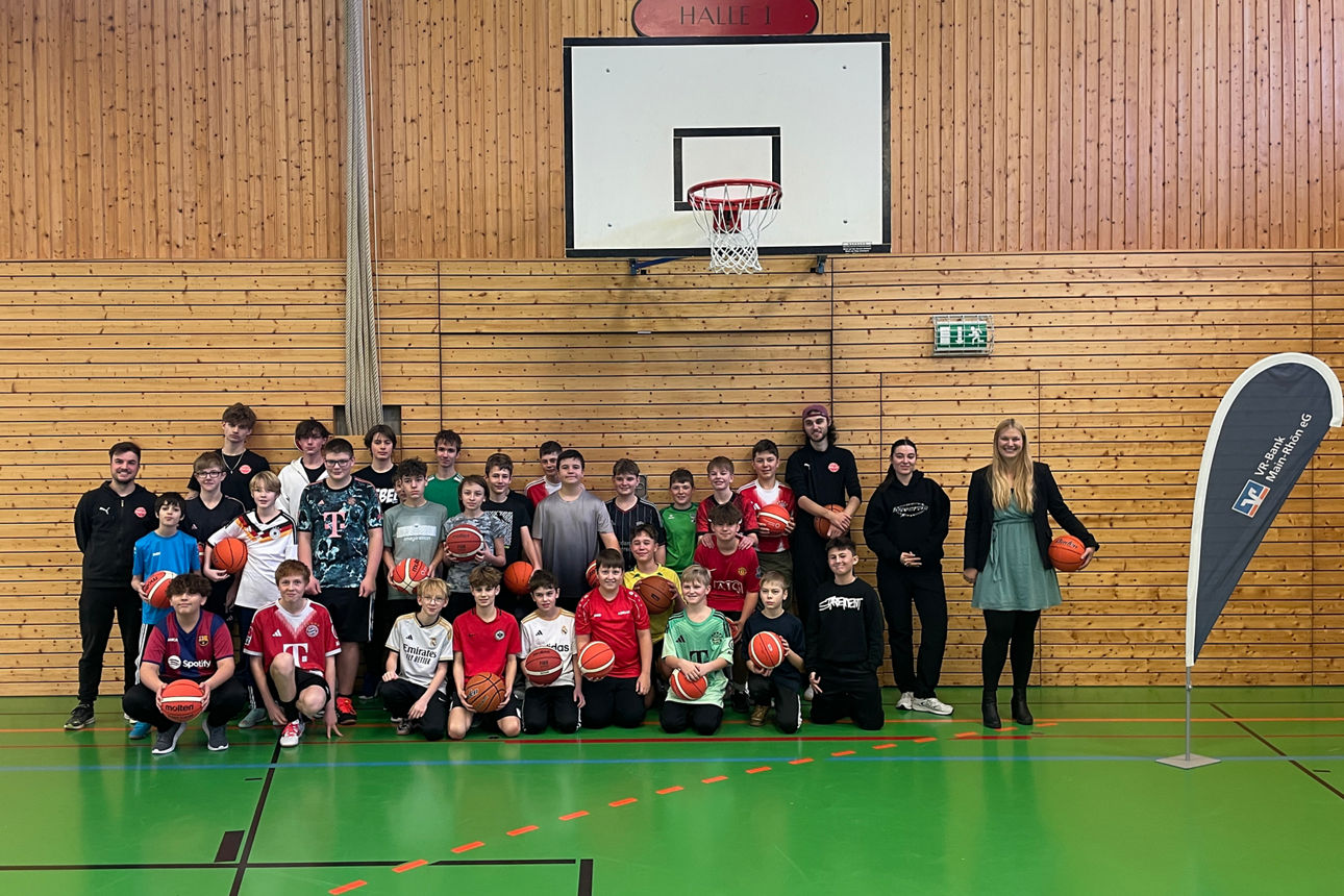 Zu sehen ist das das Jugendtrainerteam des Freak City Bamberg e.V. mit Schülerinnen und Schülern der Ignaz-Reder-Realschule. Das Foto wurde in einer Turnhalle gemacht.