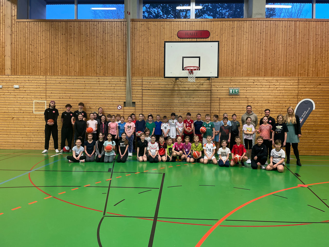 Zu sehen ist das das Jugendtrainerteam des Freak City Bamberg e.V. mit Schülerinnen und Schülern des Martin-Pollich-Gymnasiums. Das Foto wurde in einer Turnhalle gemacht.