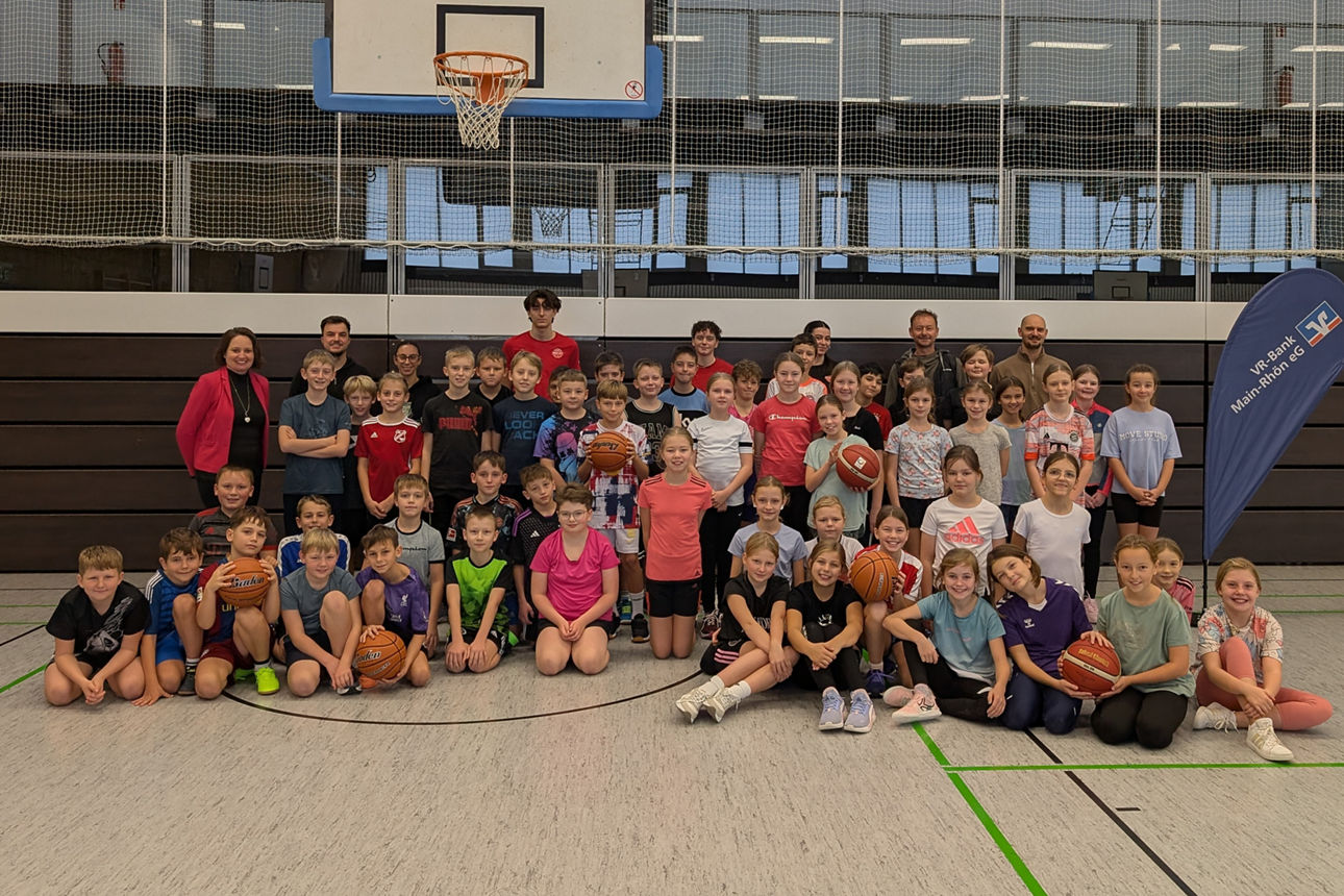Zu sehen ist das das Jugendtrainerteam des Freak City Bamberg e.V. mit Schülerinnen und Schülern der fünften Jahrgangsstufe. Das Foto wurde in einer Turnhalle gemacht.