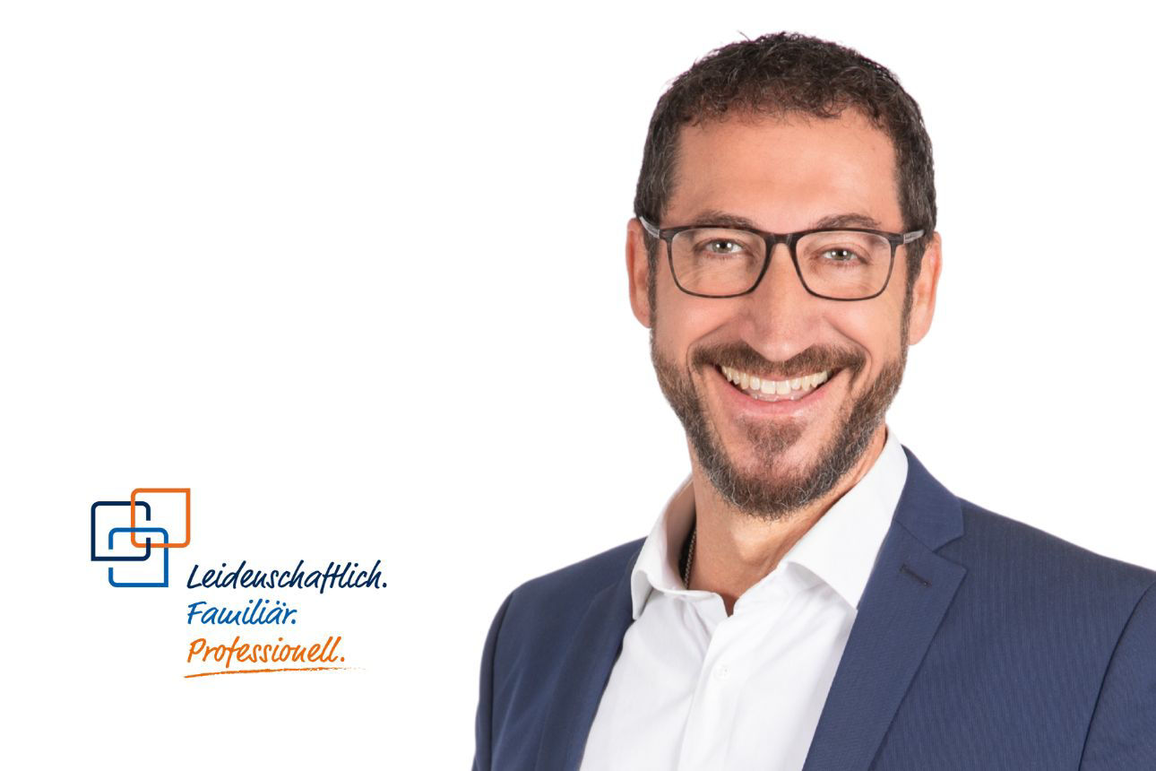 Porträt von Friedrich Linecker, einem lächelnden Mann mit Bart und Brille im blauen Anzug mit weißem Hemd. Daneben das Firmenlogo und der Slogan "Leidenschaftlich. Familiär. Professionell."