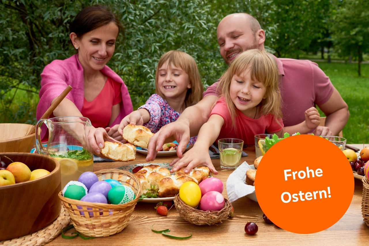 Familie sitzt am gedeckten Ostertisch, darauf ganz viele Ostereier.