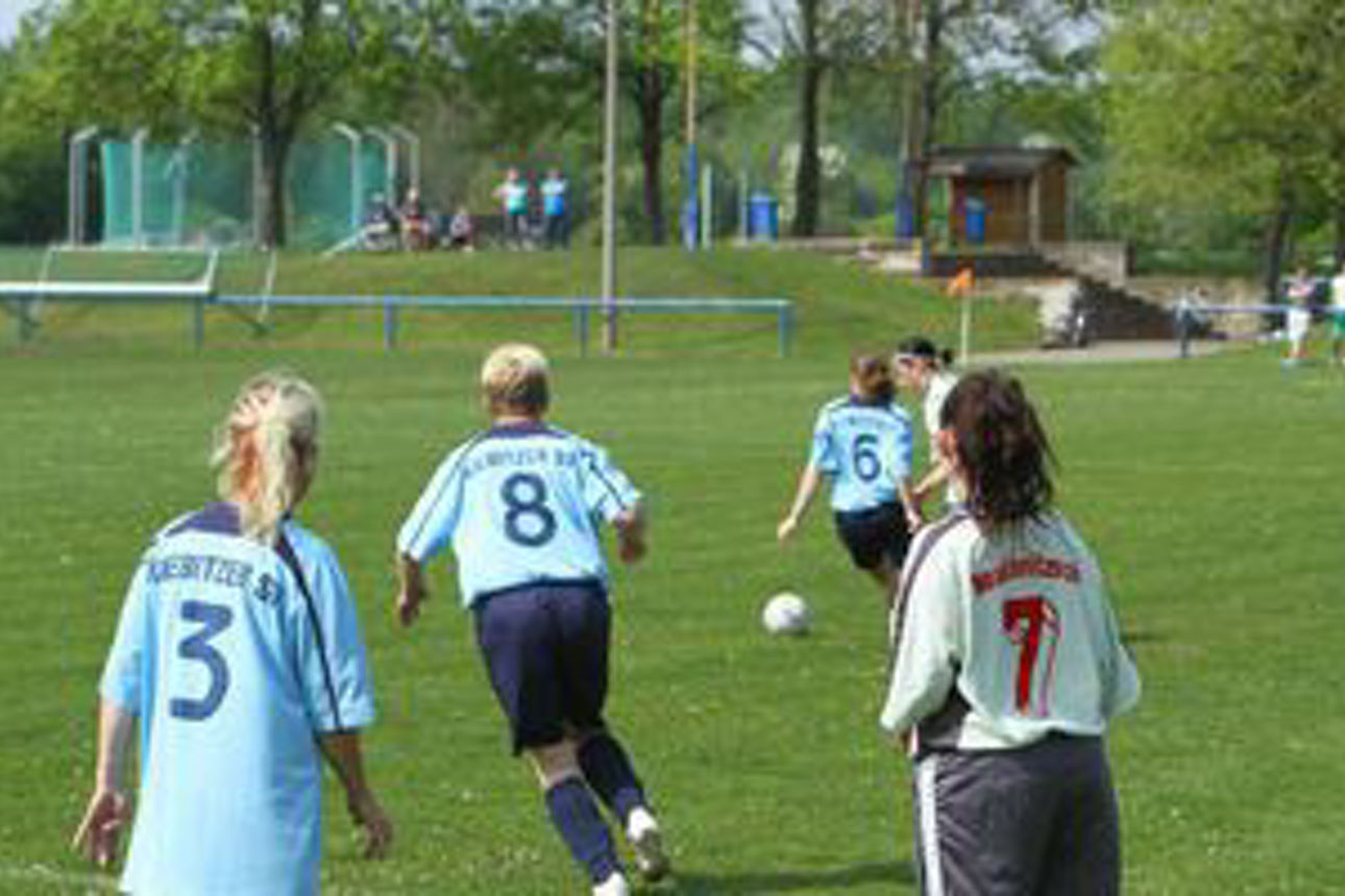 4 Kinder in Spielkleidung auf dem Fußballplatz