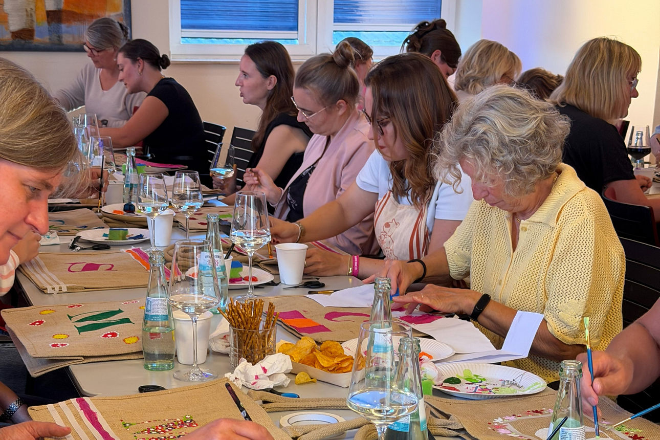 Frauen bemalen Taschen an einem Tisch