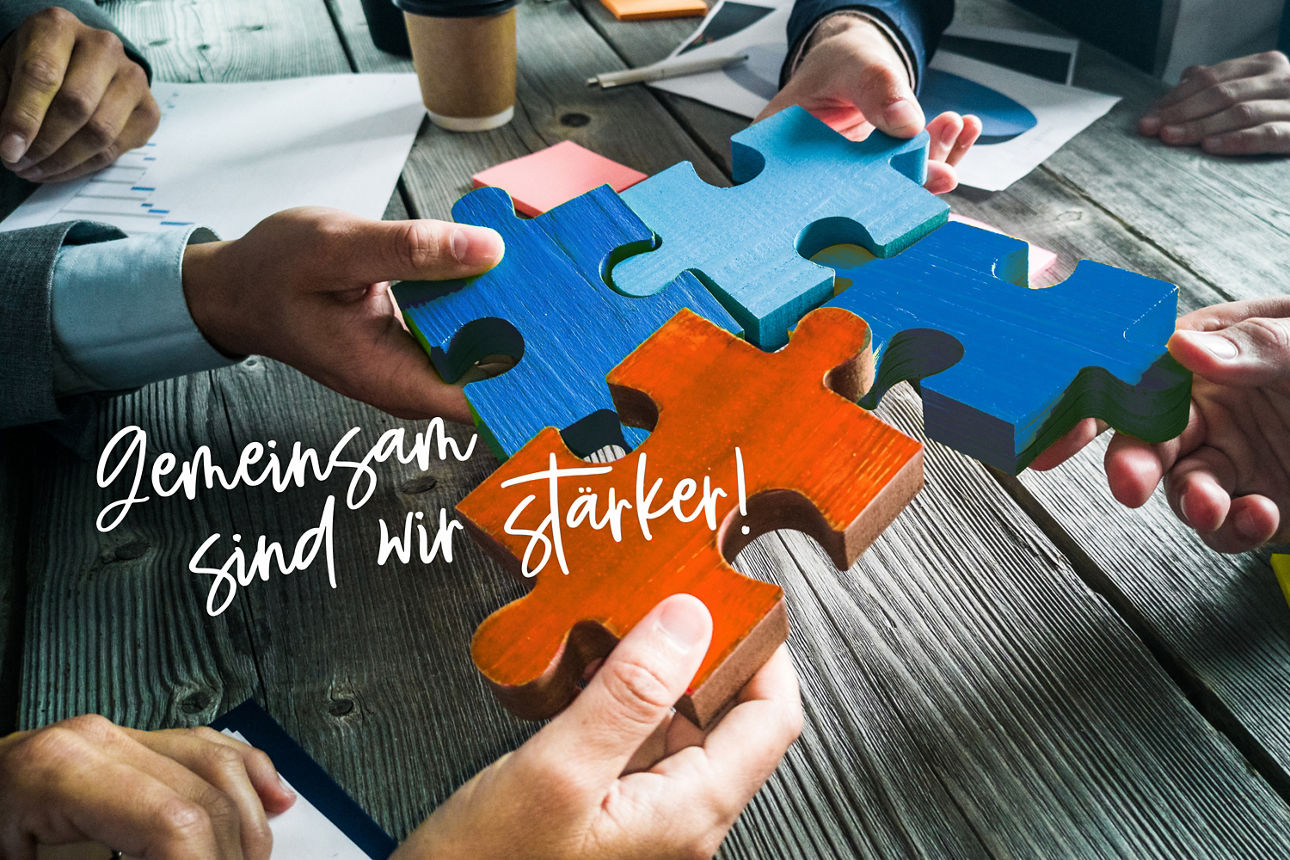 Mehrere Menschen fügen Puzzleteile zusammen, Schriftzug "Gemeinsam sind wir stärker"