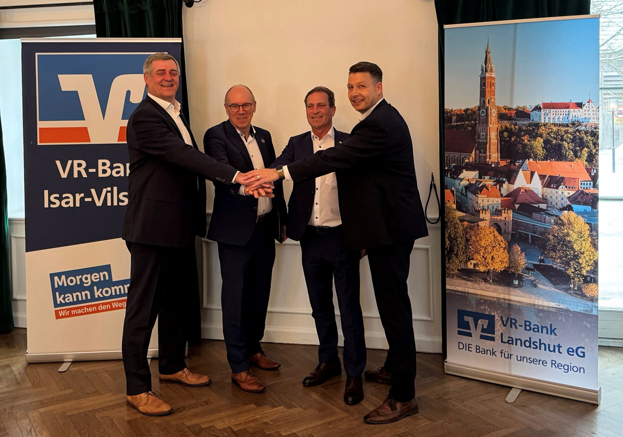 Vorstände der VR-Bank Isar-Vils eG und VR-Bank Landshut eG halten die Hände übereinander 